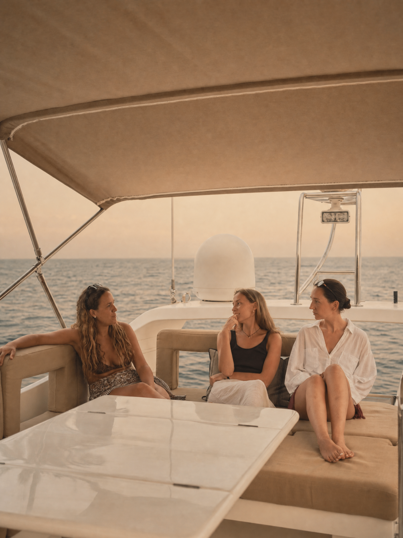 Invitadas conversando bajo el bimini del Horizon E54 en alta mar al atardecer